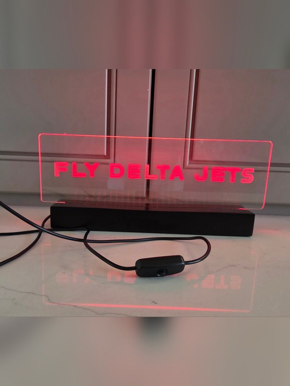 Neon Red And Clear Acrylic Display with 'DELTA JET' Logo and Black Cord